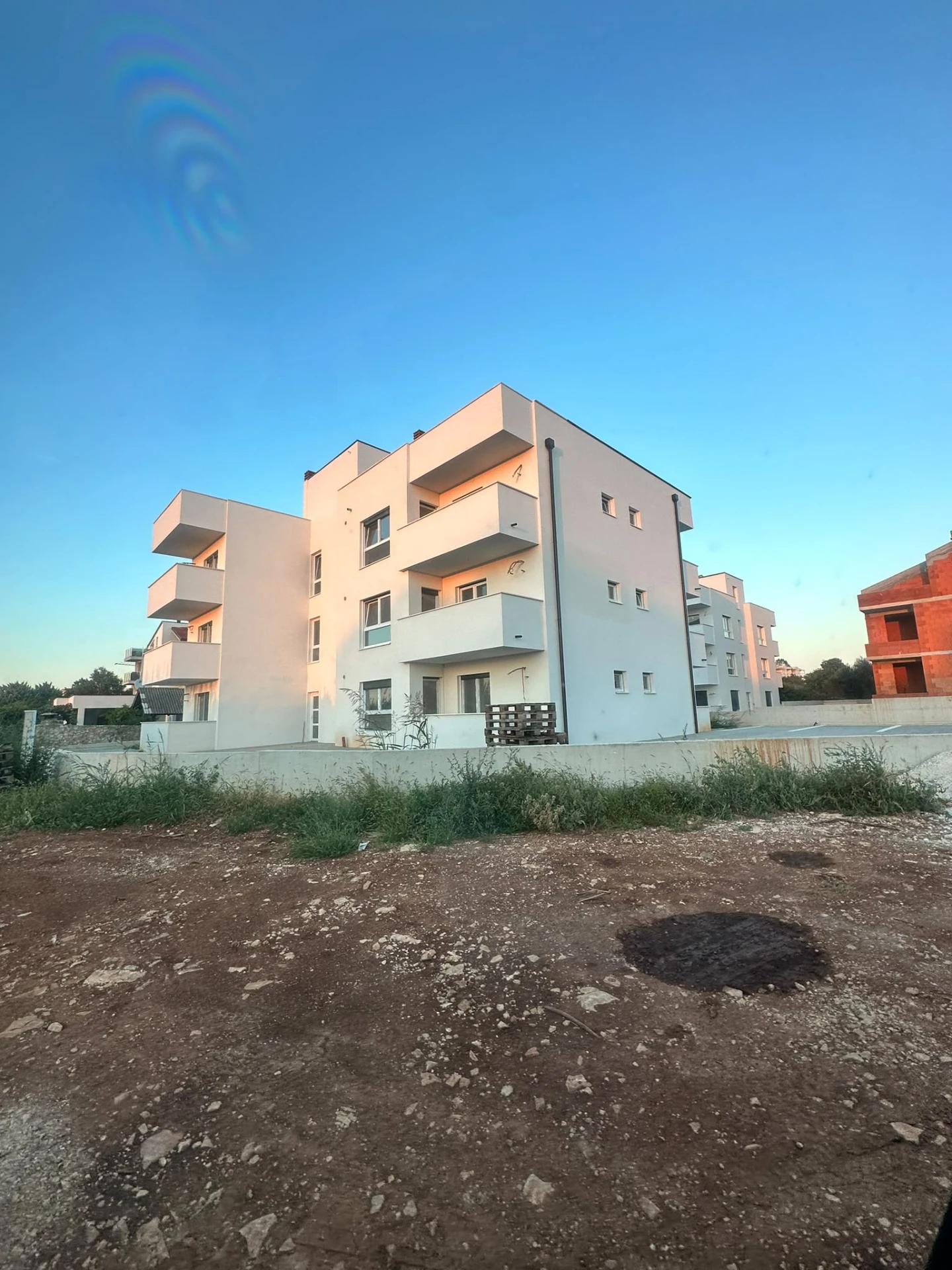 Completed white apartment building with shaded balconies at sunset