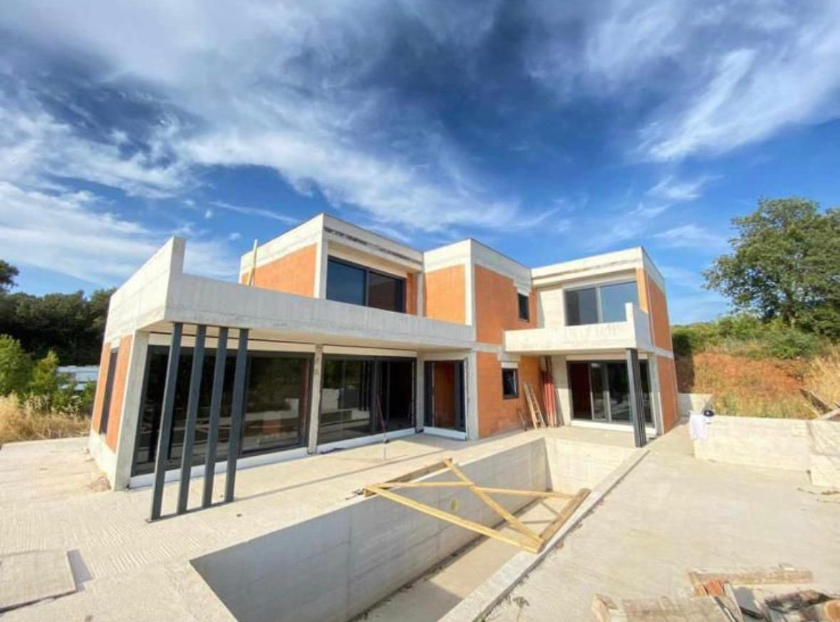 Modern villa under construction with brick and concrete volumes and a pool shell